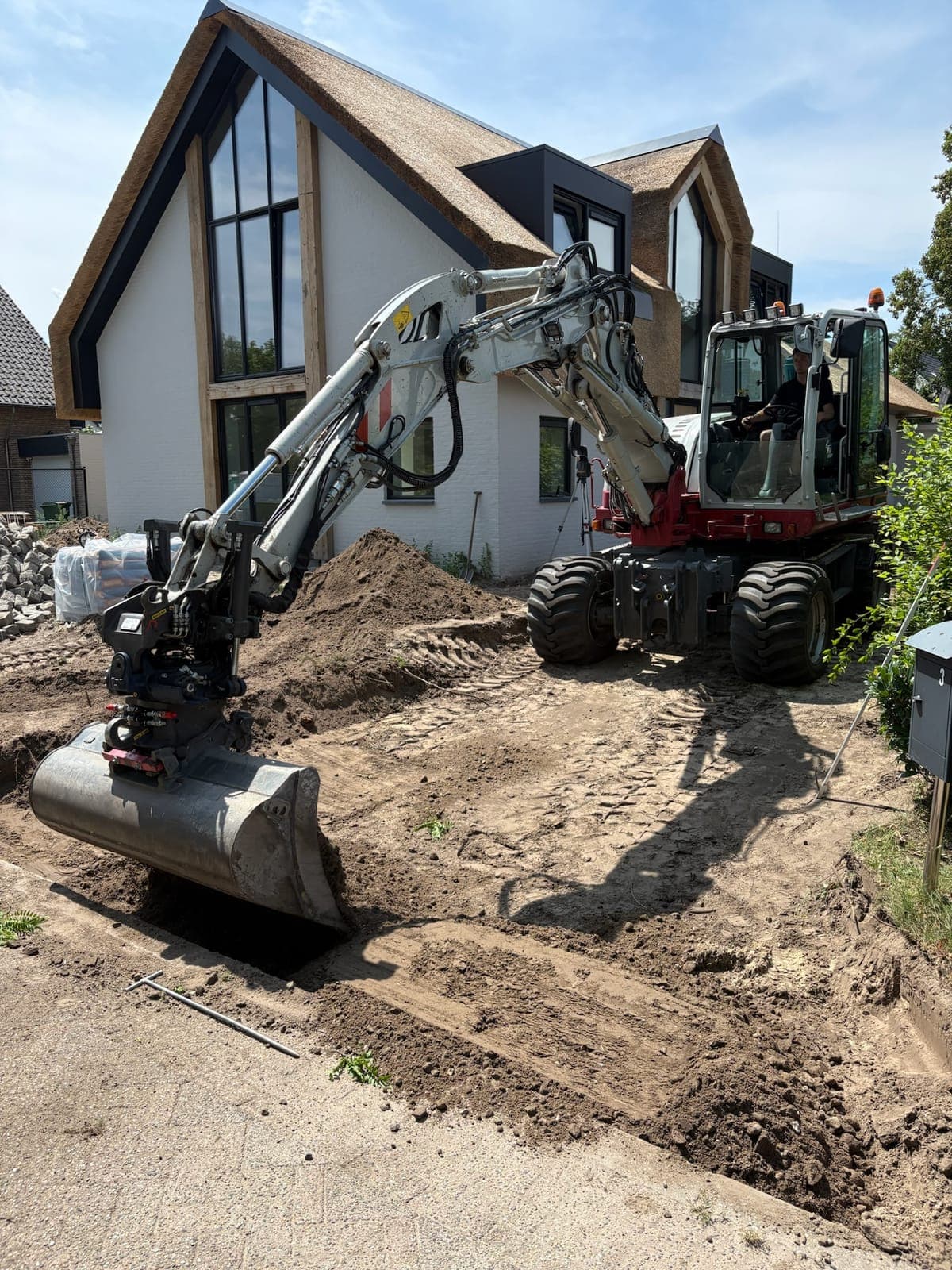 Graafmachine met bak tijdens het uitgraven van een tuin