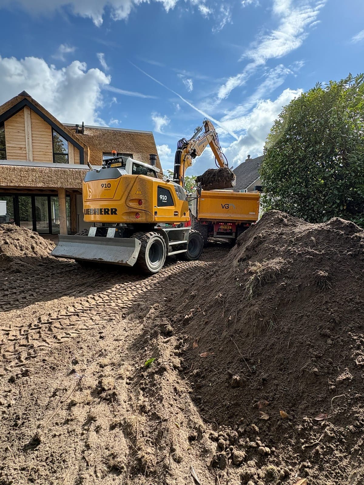 Graafmachine en dumper tijdens grondverzet bij een woning