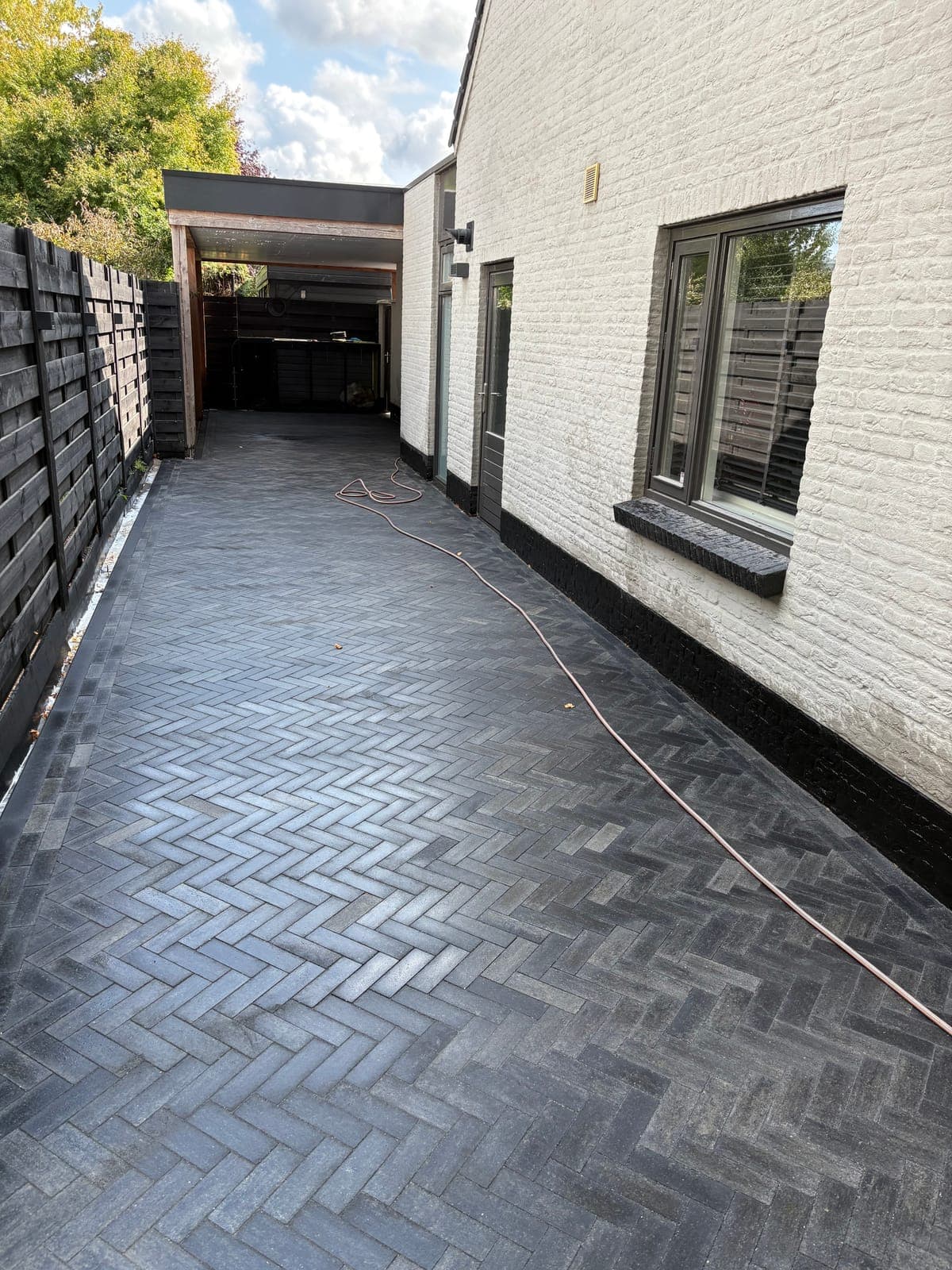 Pad in donkere klinkers langs de zijgevel
