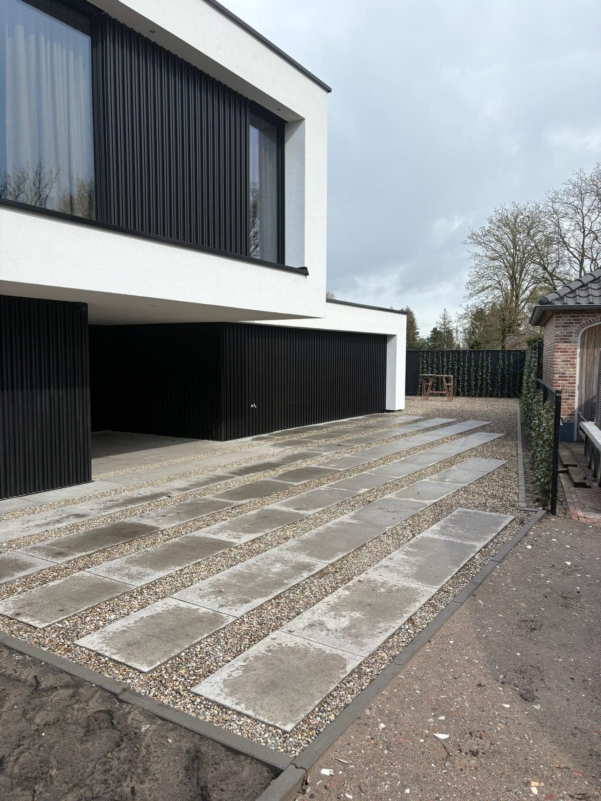 Grote betonplaten met siergrind richting de carport