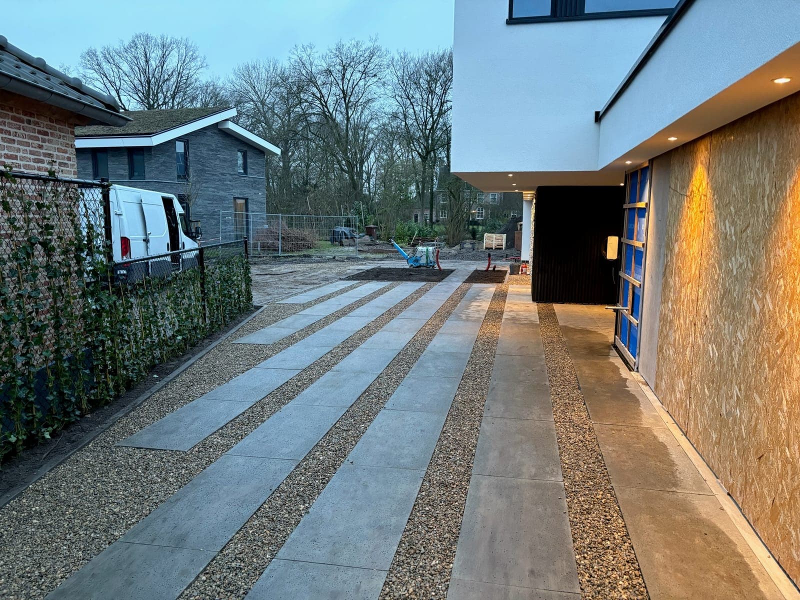 Doorlopende stroken platen en siergrind langs de woning