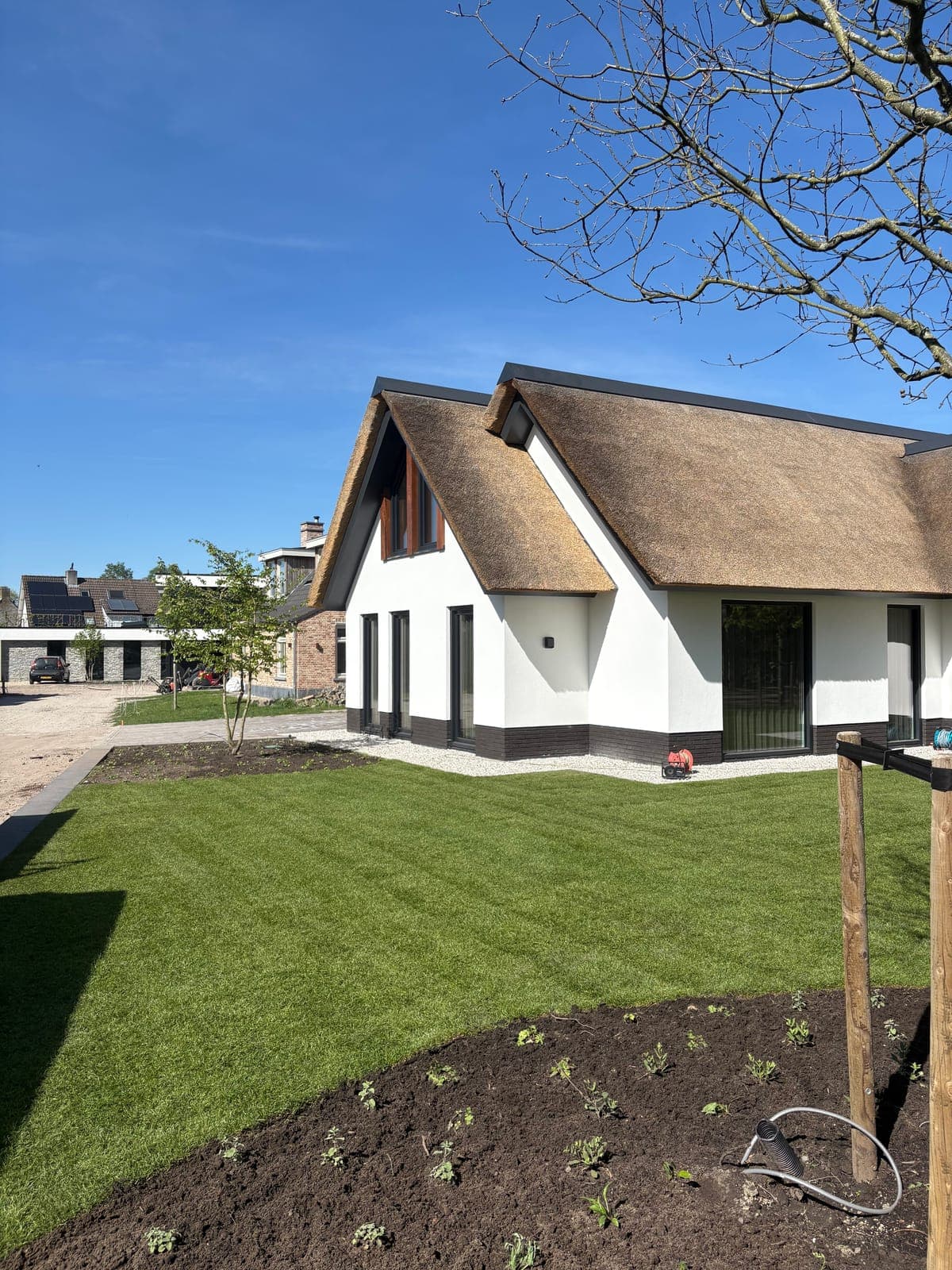 Rietgedekte woning met pas aangelegd gazon en nieuwe bomen